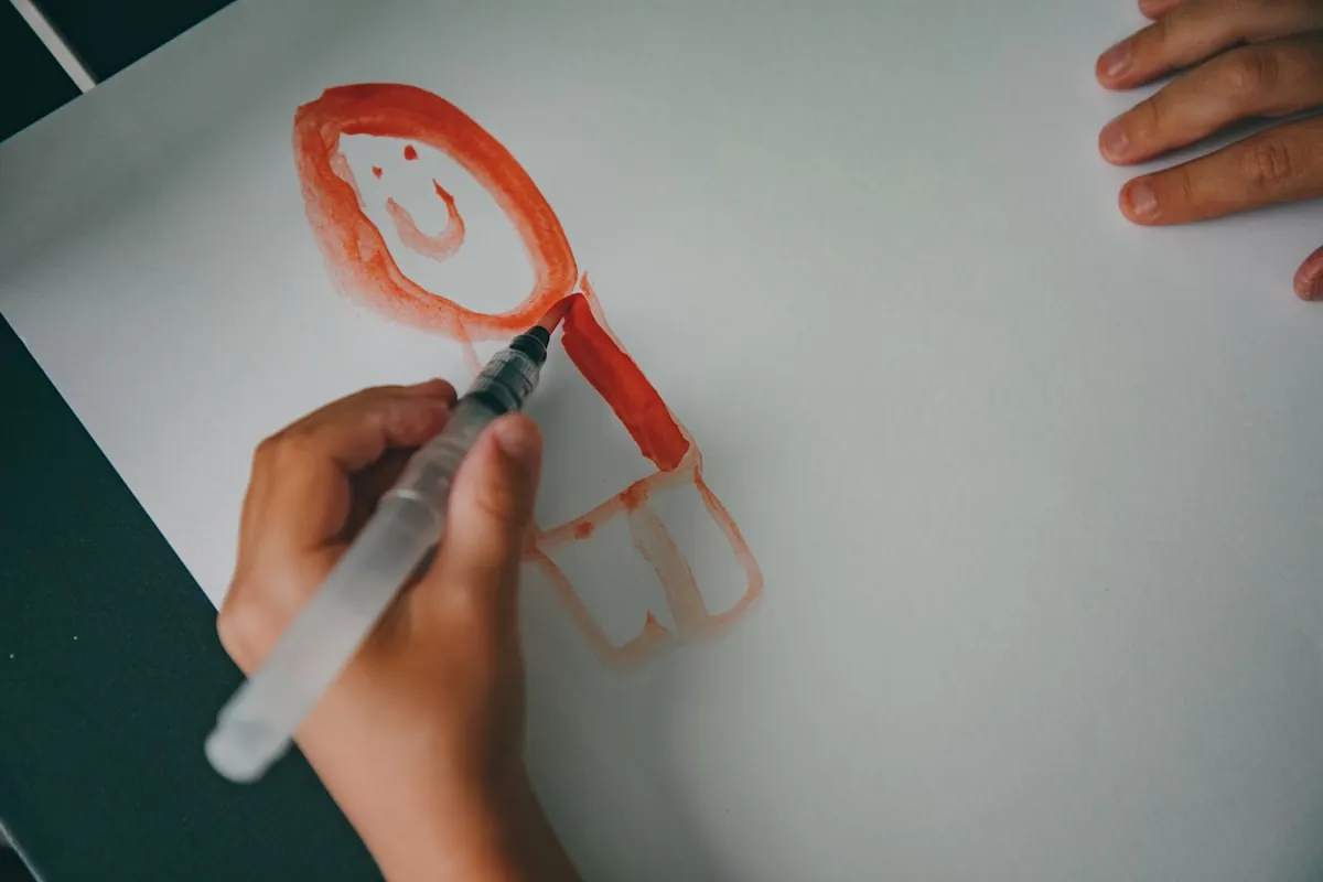Enfant qui dessine un visage souriant sur une feuille de papier
